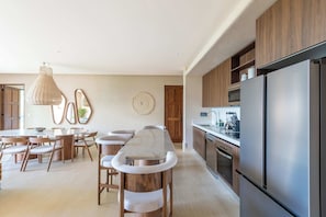 Eine moderne Küche mit einem großen Kühlschrank, Holzschränken und einem Essbereich mit rundem Tisch und Stühlen.