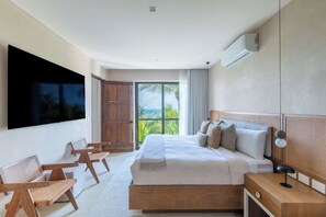 Ein modernes Schlafzimmer mit einem großen Bett, einem an der Wand befestigten Fernseher, einem Holzschrank und einem Balkon mit Meerblick.