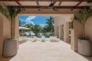 A poolside area with lounge chairs and a ceiling fan. - Artila: Oceanfront Penthouse with Rooftop (Cancún)