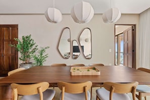 A dining area with a wooden table, six chairs, and three pendant lights. - Artila: Oceanfront Penthouse with Rooftop (Cancún)