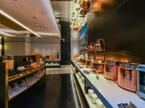 Una cocina moderna con electrodomésticos de acero inoxidable, ollas de cobre y utensilios ordenados.
