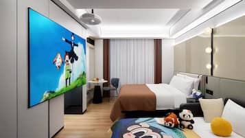 A hotel room with a large flat-screen TV, a bed with white and brown bedding, a small table with fruit, a chair, and plush toys on the bed.