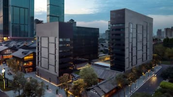 Uma área urbana moderna com edifícios altos, uma passarela para pedestres e uma rua com veículos.