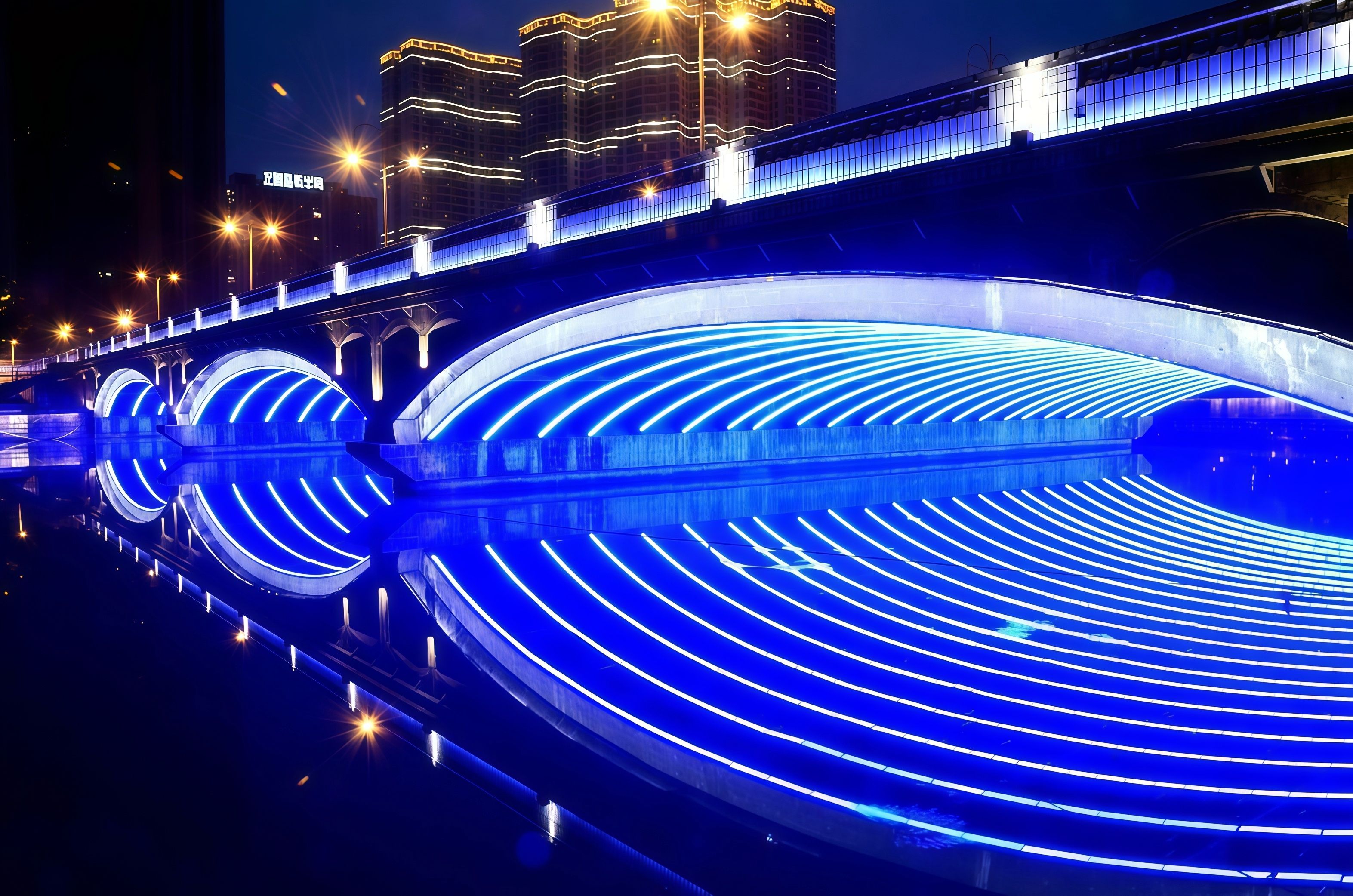 A nighttime view of a bridge with illuminated blue lights reflecting on the water.