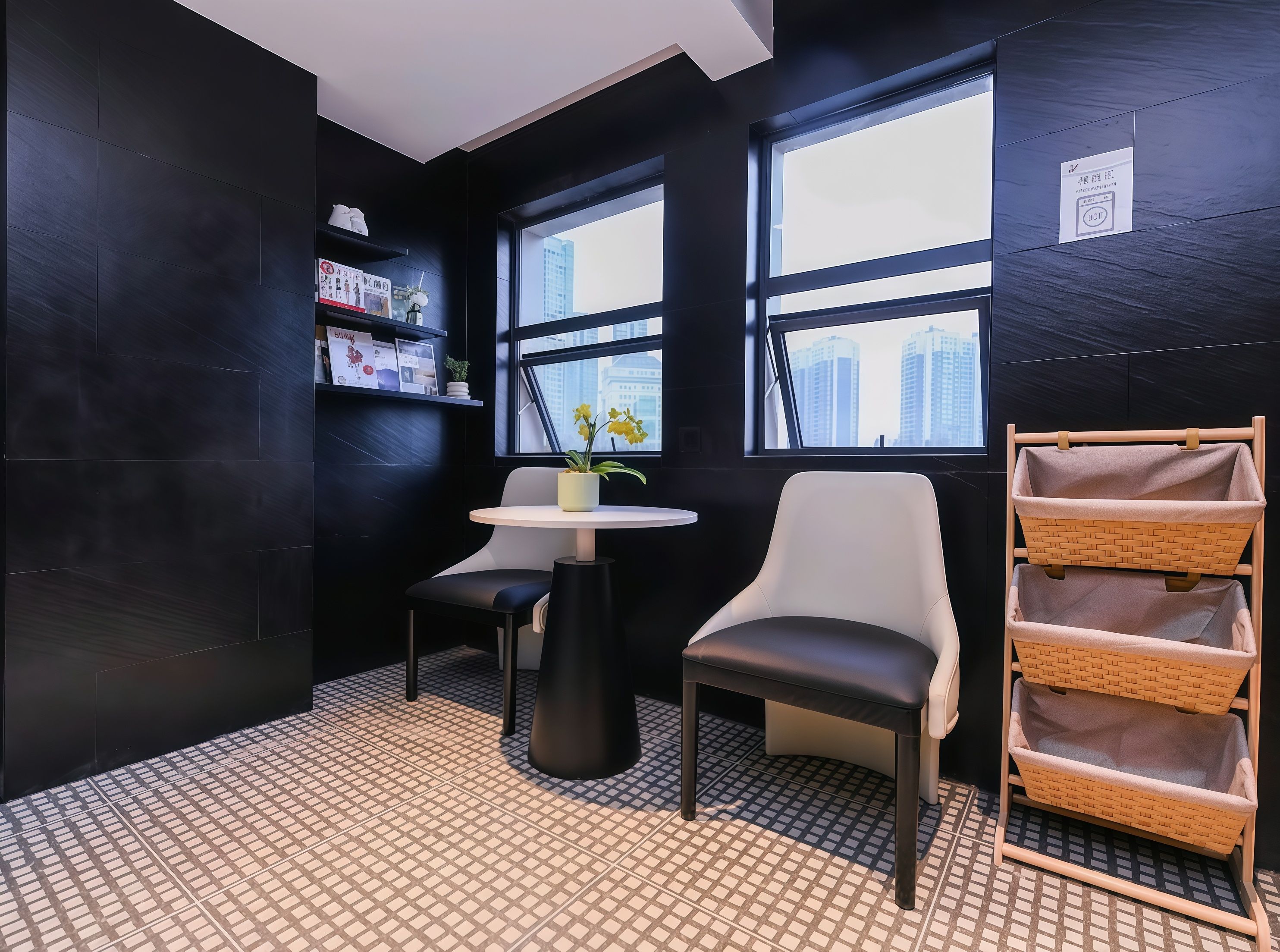 A modern room with a black and white color scheme, featuring a round table, a chair, a shelf with items, and a view of buildings through large windows.