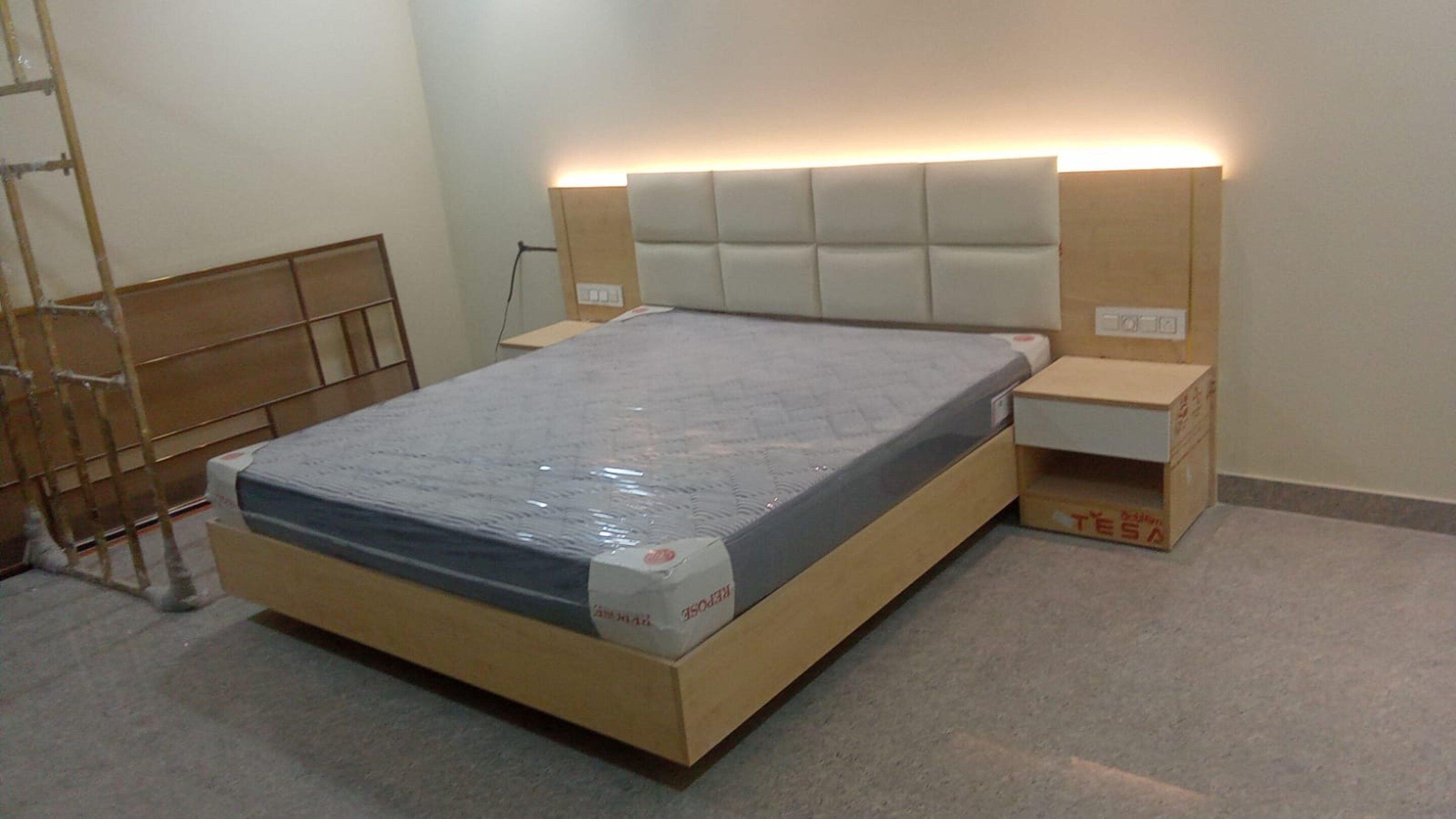 Una camera da letto con un letto, testiera, comodini e una scala.