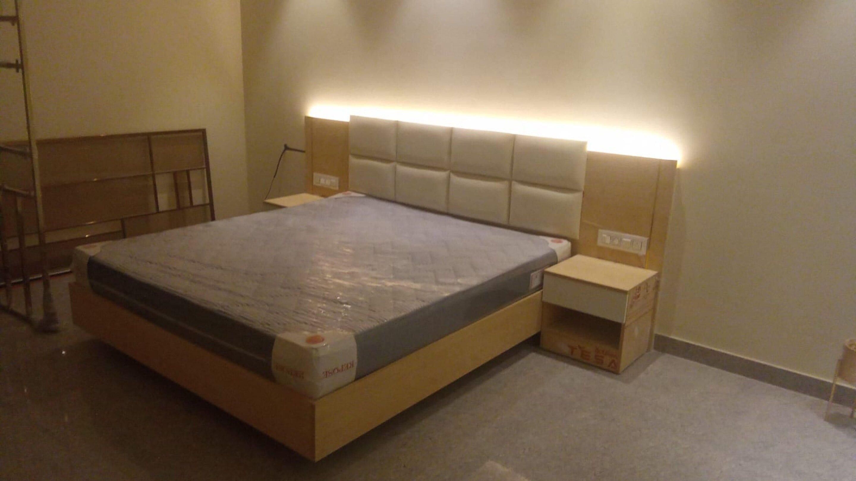 A bedroom with a bed, bedside tables, and a headboard with built-in lighting.