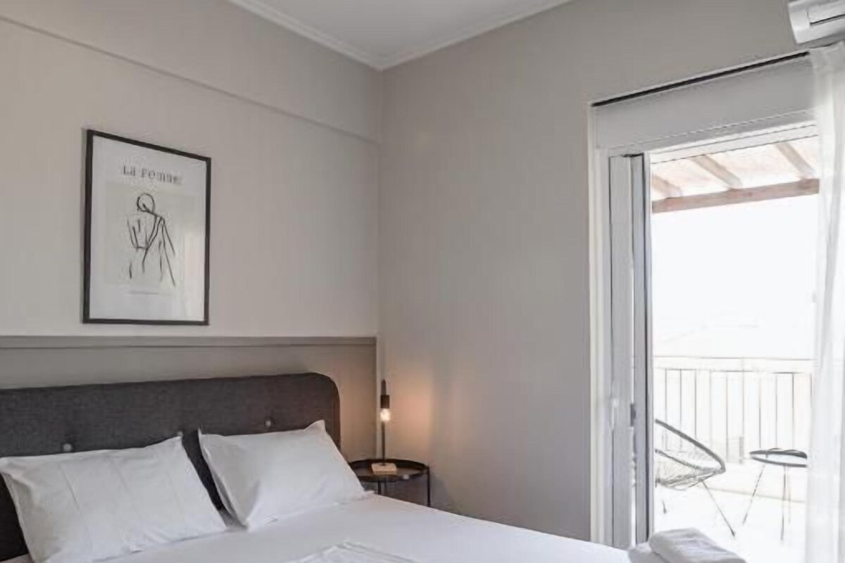 Una habitación de hotel con una cama, un ventilador de techo, un cuadro enmarcado en la pared y una ventana con vistas.