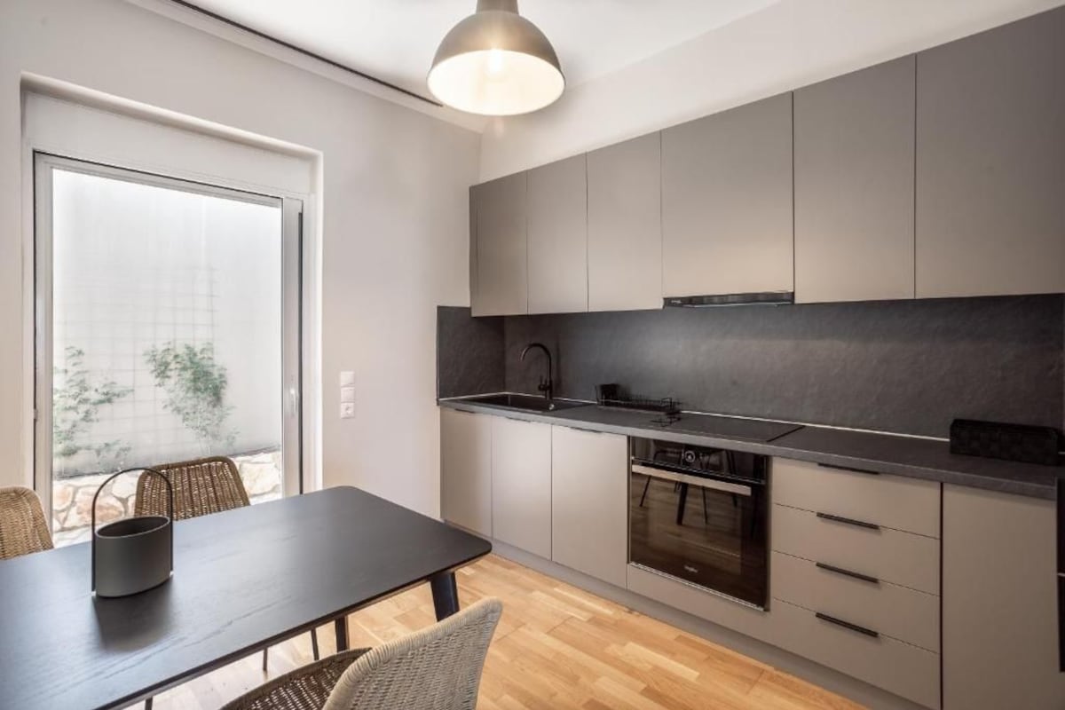 Una cocina moderna con encimera oscura, electrodomésticos de acero inoxidable y armarios de colores claros.