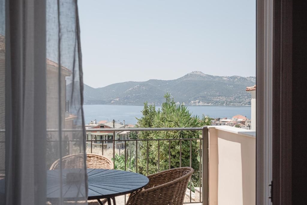 A balcony with a table and chairs, overlooking a body of water and distant hills.