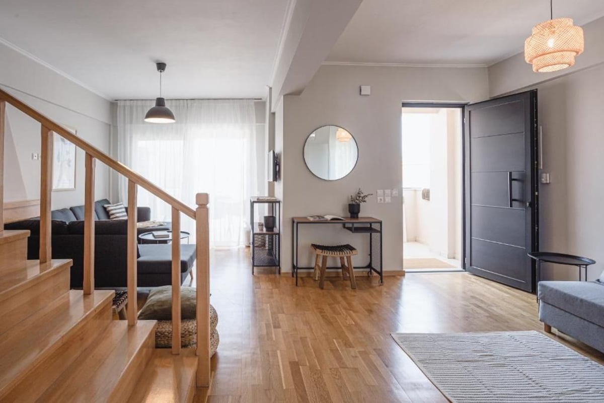 Una sala de estar moderna con una escalera, un espejo redondo y una puerta que da a otra habitación.