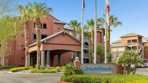 L’entrée d’un hôtel, avec un passage couvert, des palmiers et une enseigne indiquant « Westmark by Wyndham ».