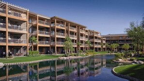 Un hôtel à plusieurs étages doté de balcons, d’une piscine et de jardins aménagés.