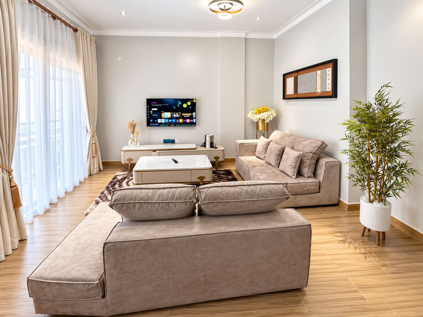 A modern living room with a sectional sofa, a coffee table, a flat-screen TV, and a potted plant.