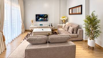 A modern living room with a sectional sofa, a coffee table, a flat-screen TV, and a potted plant.