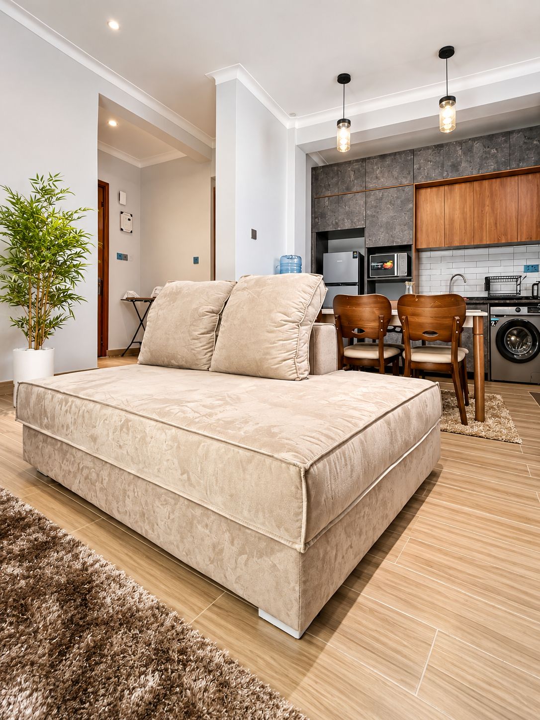 Un dormitorio moderno con una cama grande, una pequeña zona de comedor con sillas y una cocina equipada.