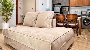 Un dormitorio moderno con una cama grande, una pequeña zona de comedor con sillas y una cocina equipada.