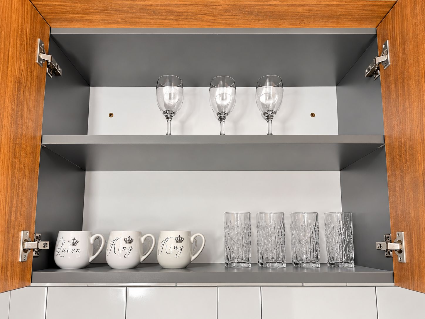 Un meuble de cuisine à deux étagères, l’une servant à ranger les verres à vin et l’autre, les tasses et les verres.