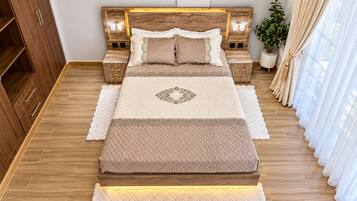 Ein Schlafzimmer mit einem Bett, Nachttischen, einem Kleiderschrank und einer Topfpflanze.
