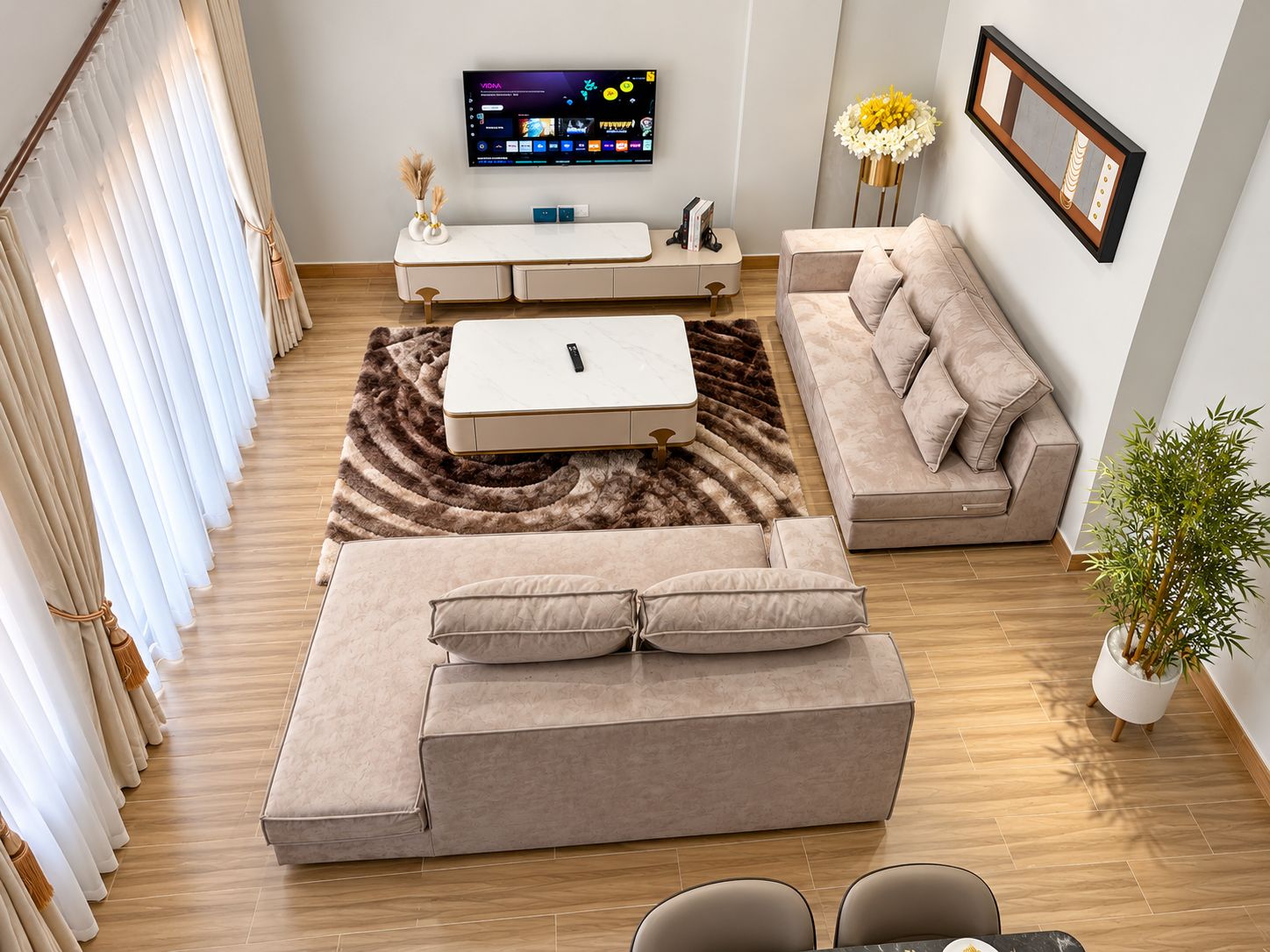 A modern living room with a sofa, a coffee table, a TV, and a plant.