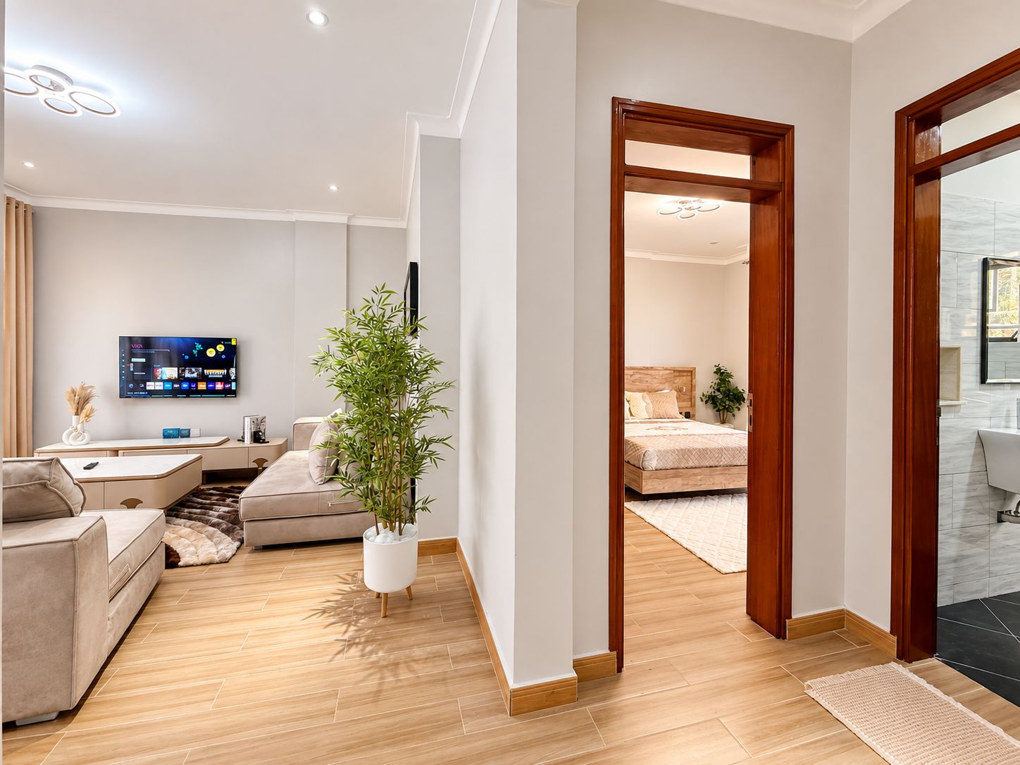 A modern living room with a flat-screen TV, a sofa, a coffee table, and a potted plant.