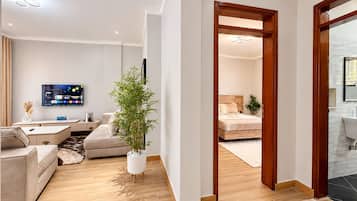 A modern living room with a flat-screen TV, a sofa, a coffee table, and a potted plant.