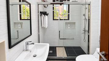 A modern bathroom with a glass-enclosed shower, a white sink, and a toilet.