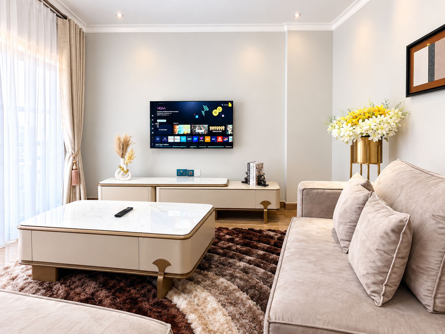 Una sala de estar moderna con un televisor de pantalla plana, un sofá, una mesa de centro y un jarrón decorativo con flores.