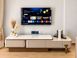 A flat-screen TV mounted on a wall displaying a streaming service interface with various TV channels and original content. - Advanced Homes (Kampala)