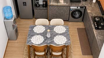 A compact kitchen with a dining area, including a refrigerator, coffee maker, and washing machine.