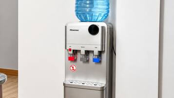 A water dispenser with a large water bottle on top, a control panel with temperature settings, and a sign indicating no smoking.