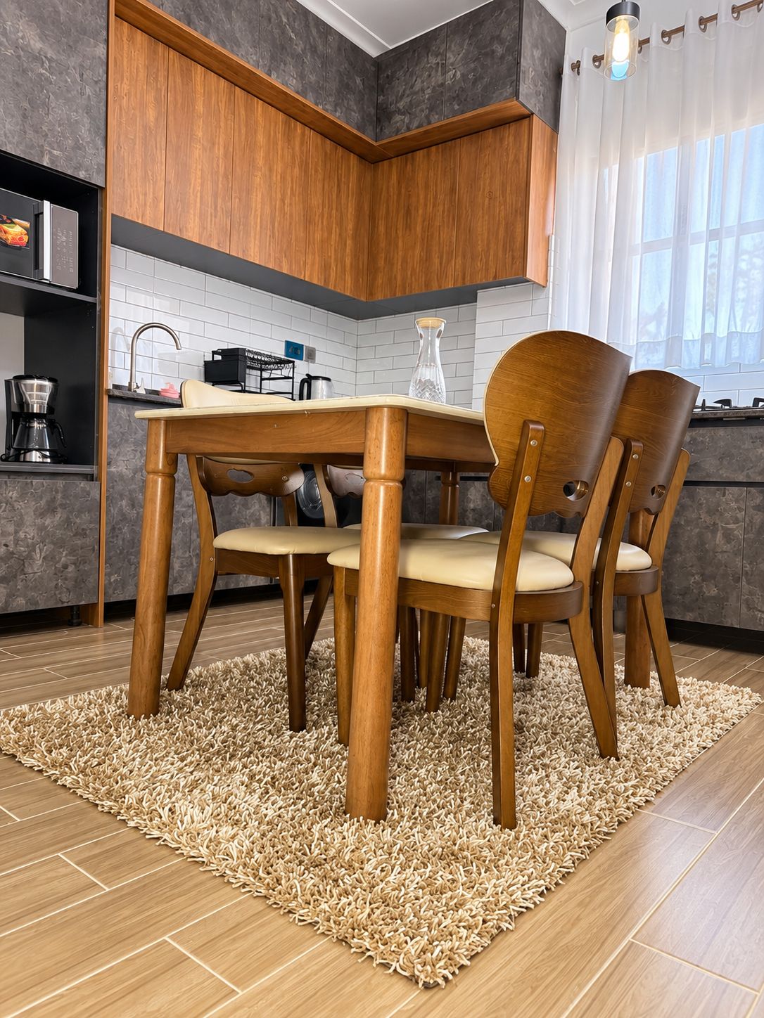 Cozinha moderna com armários de madeira, mesa de jantar com cadeiras e um tapete no chão.