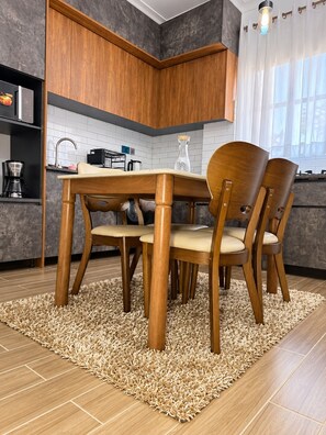 A modern kitchen with wooden cabinets, a dining table with chairs, and a rug on the floor. - Advanced Homes (Kampala)