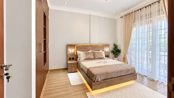 A bedroom with a wooden headboard, a bed with a quilted cover, a nightstand, a wall-mounted light, and a window with curtains.