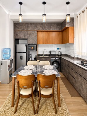 A modern kitchen with a dining area, featuring a refrigerator, microwave, sink, and a water dispenser. - Advanced Homes (Kampala)