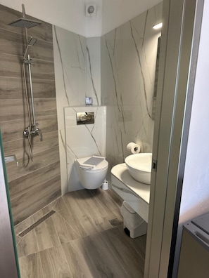 Un baño moderno con ducha, inodoro y lavamanos.