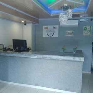 Taulell de recepció amb un ordinador, una bandera i un cartell penjat a la paret.