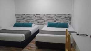 Una habitació amb dos llits, una taula petita i una cadira.