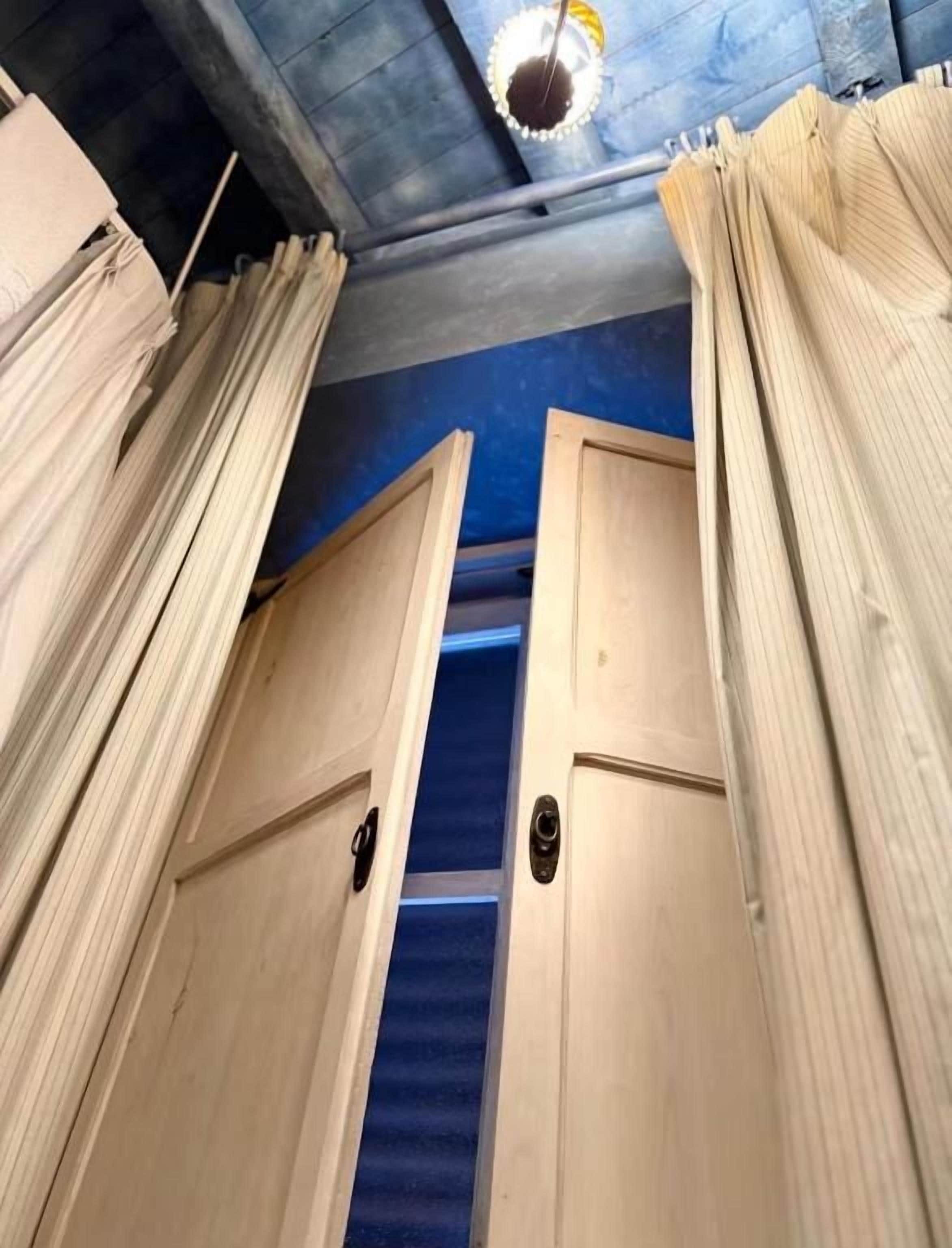 A corridor with wooden doors and curtains, leading to a room with a blue carpet.