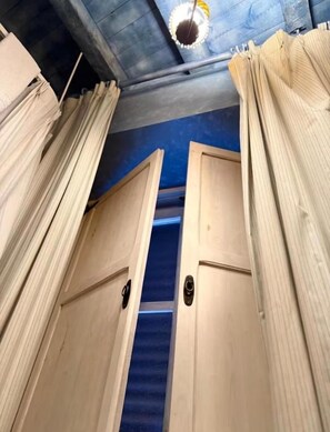 Un couloir avec des portes en bois et des rideaux, qui mène à une pièce dont le sol est recouvert d’une moquette bleue.