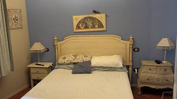 A bedroom with a bed, nightstands, a dresser, a chandelier, and a wall-mounted picture.