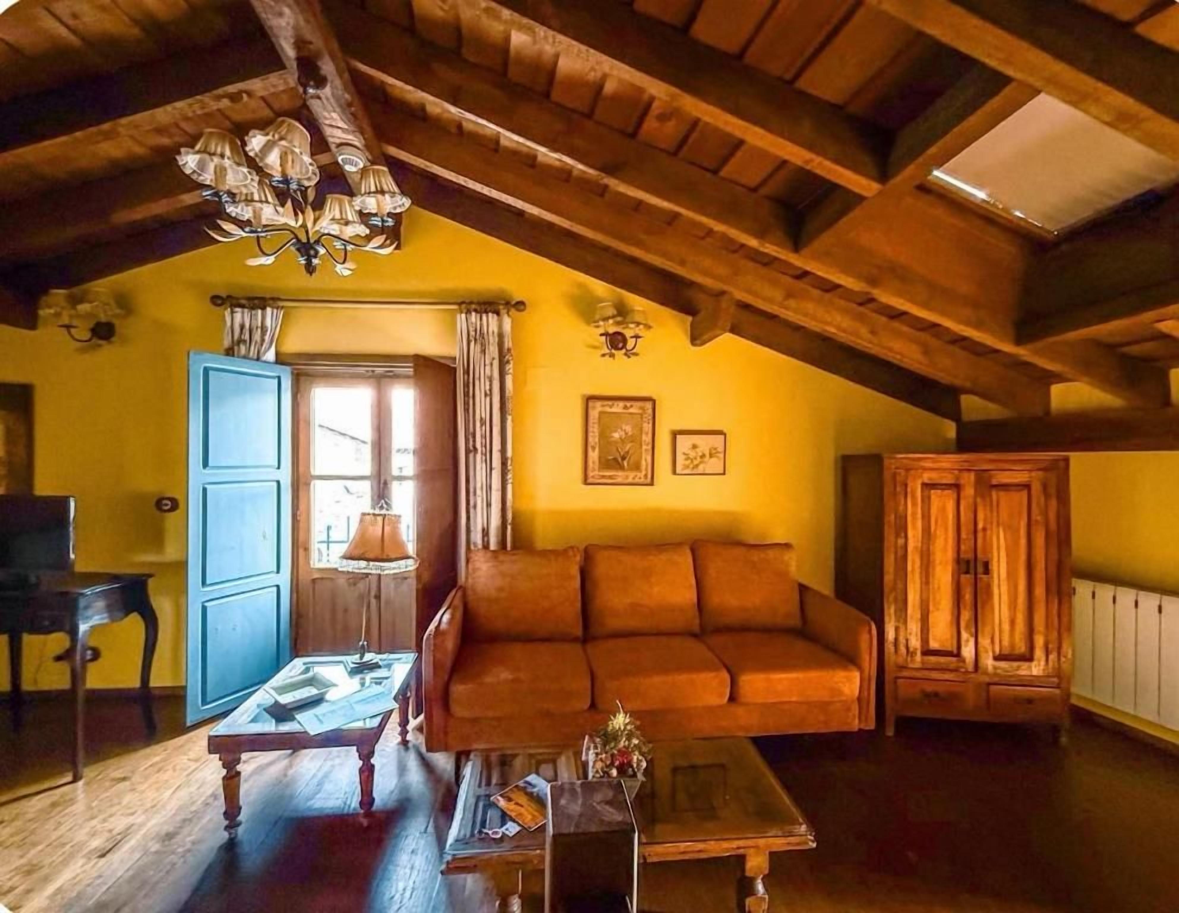 Una sala acogedora con techo de madera, un sofá, una mesa y un aparador.