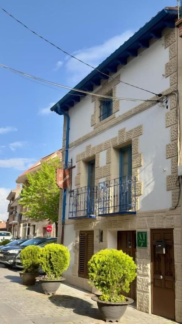 A building with a balcony, potted plants, and a clear sky.