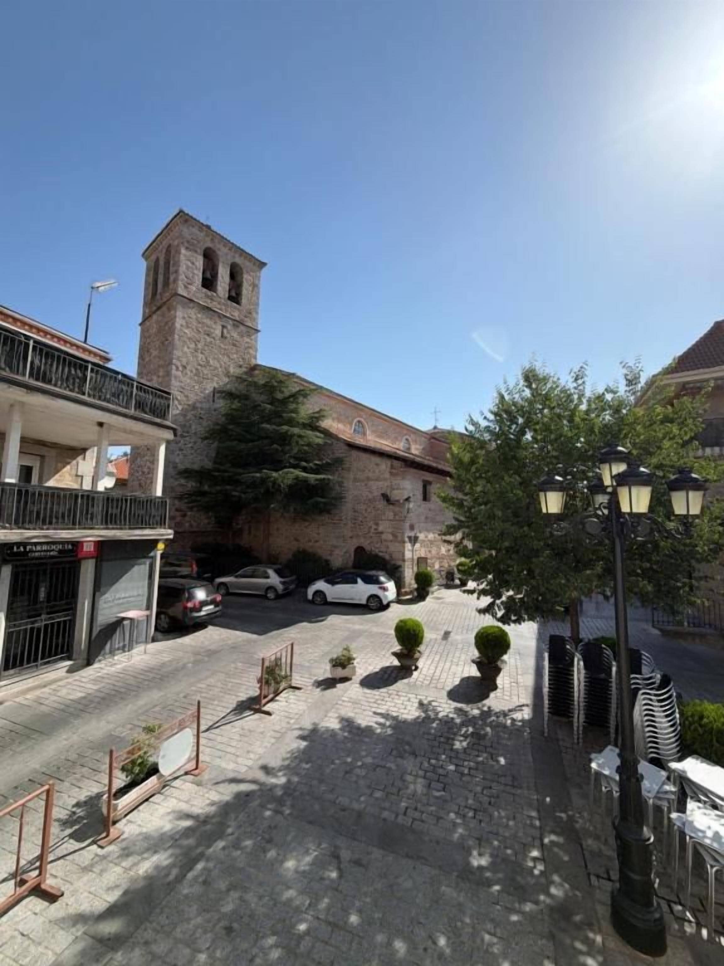 Una calle con un edificio histórico, un coche estacionado y una cafetería.