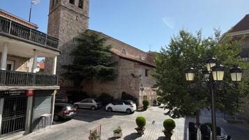 Una calle con un edificio histórico, un coche estacionado y una cafetería.