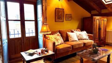 Una sala de estar acogedora con un sofá, una mesa de centro y una lámpara. Hay una ventana con cortinas y una puerta con marco de madera.