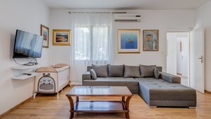 Un salon moderne avec un canapé, une table basse, un téléviseur et des œuvres d’art accrochées aux murs.