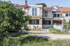 Un immeuble de deux étages doté d’un balcon, d’une antenne parabolique et d’un vélo garé à l’extérieur.