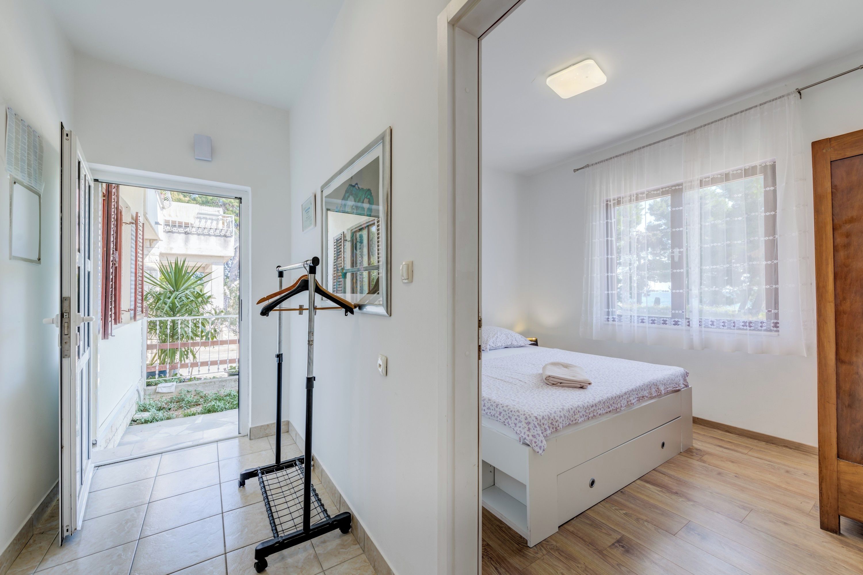 A bedroom with a bed, a mirror, and a door leading to a balcony.