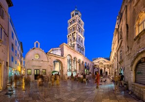 A historic square with a prominent bell tower, a dome, and a covered walkway. - Beachfront Sunshine apartment with garden in center (Split)